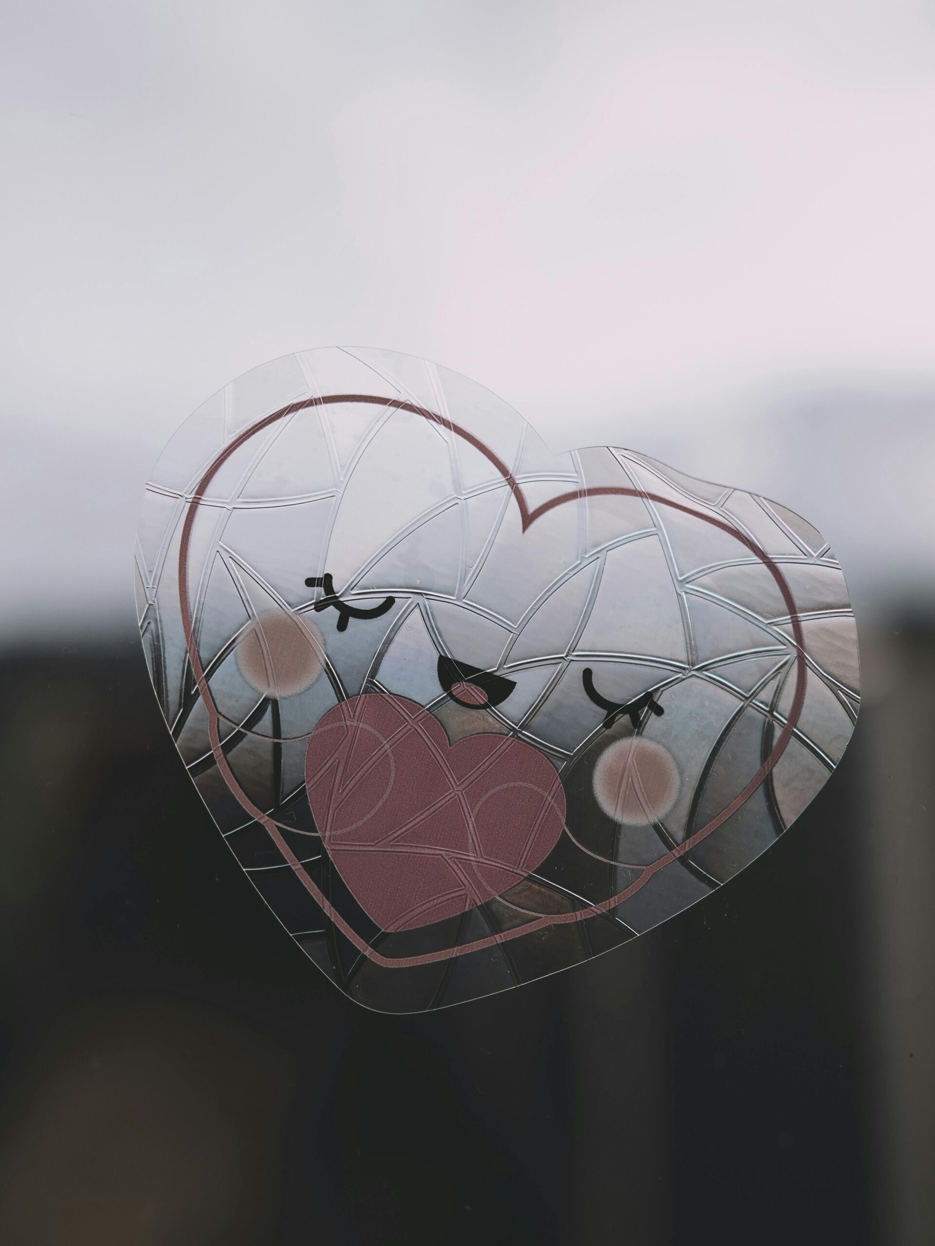 Adorable heart-shaped sticker with a smiling face on a window, creating a charming decoration.